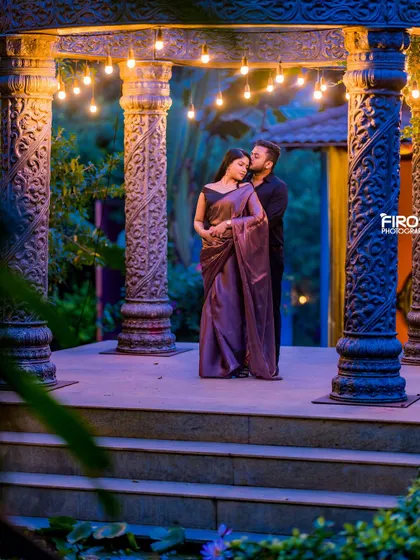 A romantic portrait under the stone archway, lit by soft, warm lights. The evening ambiance adds a layer of intimacy and drama to this beautiful ethnic wear shot.