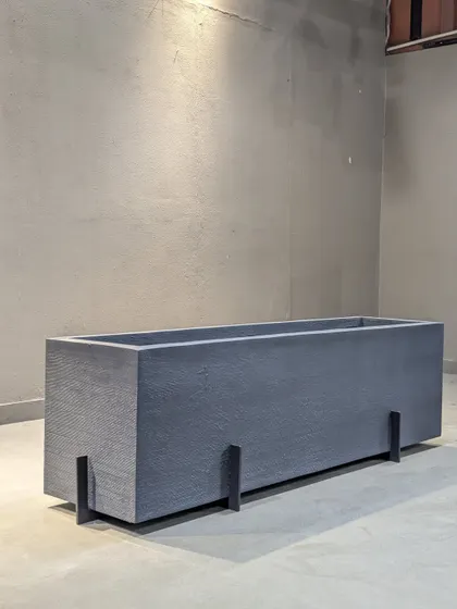 This sleek, rectangular planter in a dark grey finish is made from lightweight fiber. Its modern, minimalist design is perfect for creating clean lines in both outdoor and indoor settings.