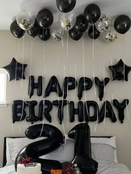 A sleek and simple 21st birthday room decoration. Black balloons, "Happy Birthday" foil letters, and large number foils create a cool and modern vibe.