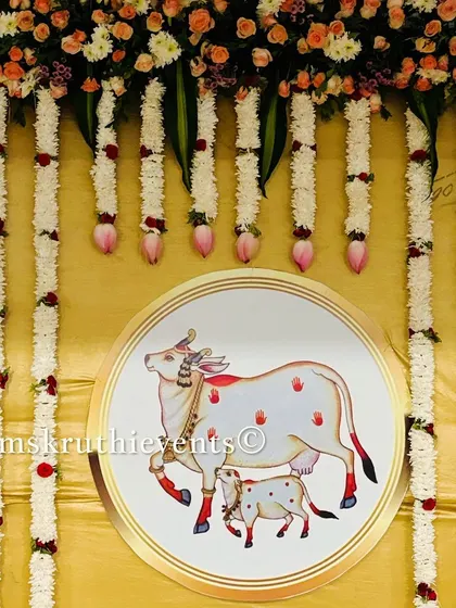 A close-up of the central motif in our cow-themed decoration. The illustration of the cow and calf is framed by hanging garlands of jasmine and lotus buds, adding to the serene and traditional feel.