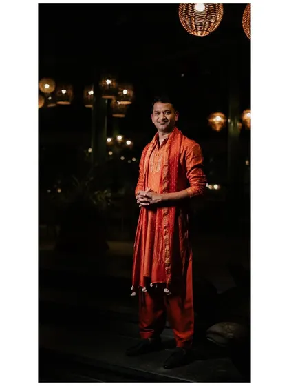 A portrait of the groom in his custom-made orange Patiala set. The vibrant color was a perfect choice for the festive Mehendi night.