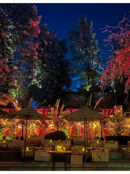 The outdoor seating area of the jungle party, illuminated with dramatic red and yellow lights. The use of color transforms the natural landscape into a surreal, high-energy environment.