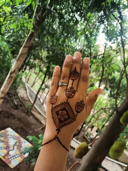 A beautiful shot of the jewellery-style mehendi in a natural setting. The design looks like a delicate hand chain, perfect for a modern and chic vibe.