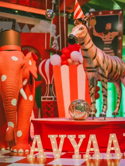 Custom props like this polka-dotted elephant and striped zebra are key elements of my circus theme. The light-up marquee letters spelling 'AVYAAN' add a personalized, celebratory touch to the decor.