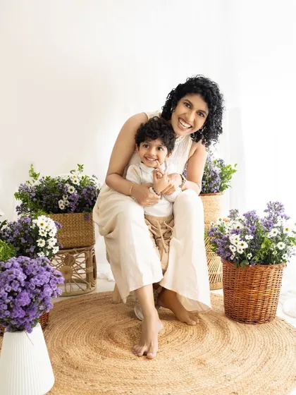 A joyful 'Mom and Son' portrait in a beautiful, light-filled studio setup with purple and white flowers.
