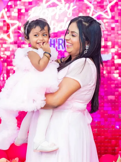 A precious moment between a mother and her daughter at her first birthday party. The all-pink theme, from the sequin backdrop to their dresses, makes this an incredibly sweet and girly shot.