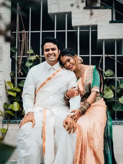 A relaxed and happy portrait of a couple in traditional South Indian attire, sharing a sweet moment on a staircase.
