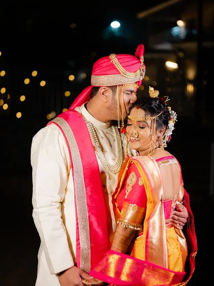 A tender moment between the couple, with the groom kissing his bride's forehead.