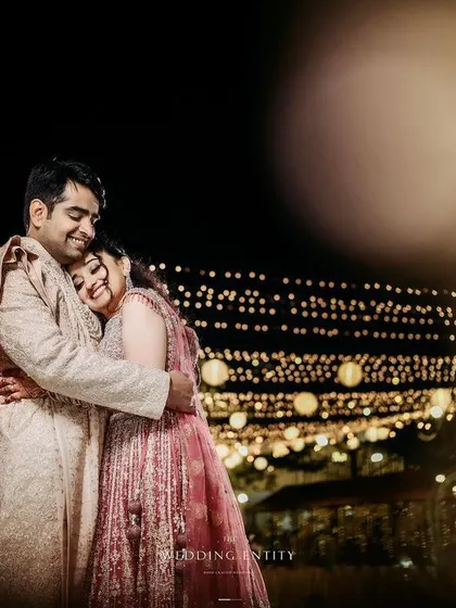A tender moment between the couple, captured under a magical canopy of string lights, creating a beautiful bokeh effect.