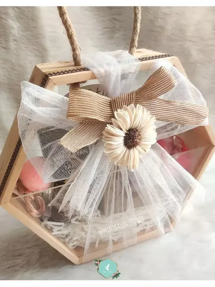 The hexagonal hamper for her, beautifully wrapped with a net, a rustic bow, and a sola wood flower. This packaging is designed to be as enchanting as the gifts inside.