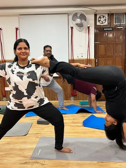 Partner yoga doesn't always have to be perfect. This fun shot captures a moment of laughter and playfulness as two students work on a combined pose.