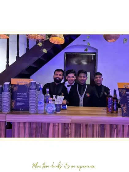 Our team of four bartenders ready for service behind a rustic wooden bar, showcasing their smart and coordinated uniforms.