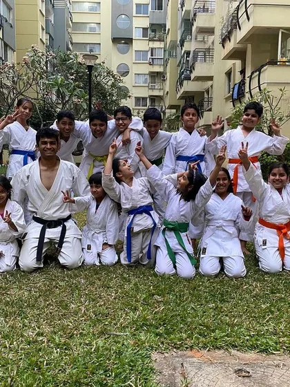 An energetic group photo with students from our Purva Belmont dojo celebrating their newly earned belts with their Sensei.