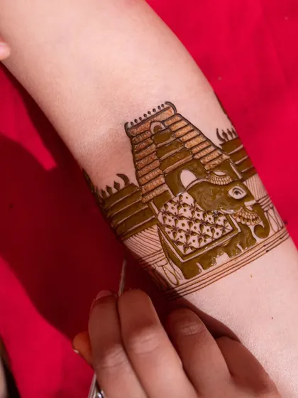 A work-in-progress shot showing the creation of a temple and elephant motif. This highlights the precision required to bring these grand traditional symbols to life in henna.
