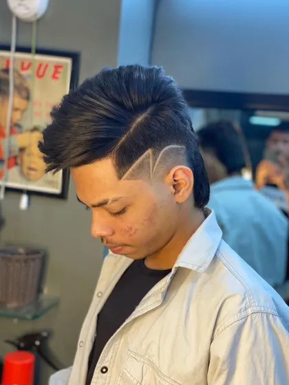 A detailed shot of a modern mullet with a custom lightning bolt design. The sharp lines are carved into the fade, showcasing my skill with intricate razor art.