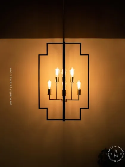 Inspired by Art Deco design, this hanging fixture features a strong geometric black frame with exposed vintage-style filament bulbs. The combination of black and warm gold tones provides a sophisticated, retro feel for dining areas or entryways.