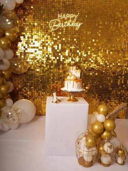 Here's a popular glam birthday setup featuring a gold shimmer wall that really catches the light. I paired it with a custom 'Happy Birthday' neon sign and a white and gold balloon garland for a complete party look.