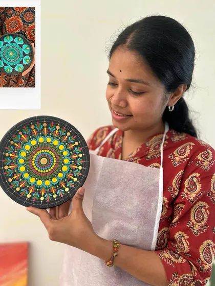 A close-up of a vibrant dot mandala plate. The artist is admiring her detailed handiwork.