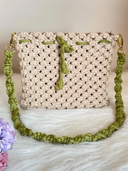 A full view of this custom cream and green macrame sling bag. The gold-tone clasps make the strap detachable, so you can also use it as a pouch.
