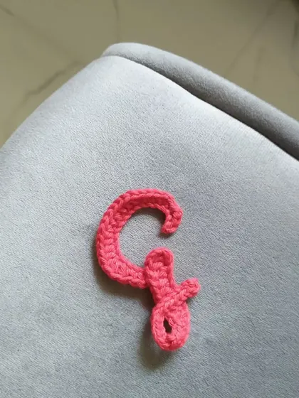 The calligraphy letter 'G' in the same pretty coral color.