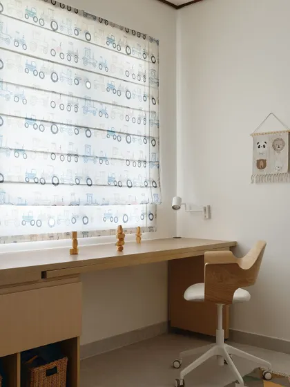 A close-up of the kids' room, showing the playful tractor-patterned roman blinds and the custom-designed, openable study desk.