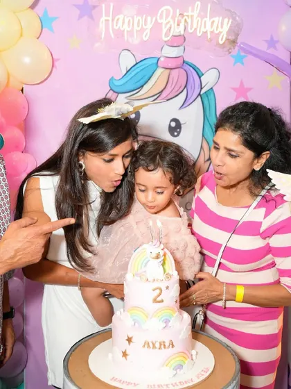 The birthday girl gets ready to blow out the candles on her adorable unicorn cake.