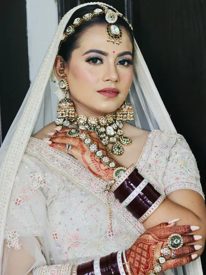 The bride's hands framing her face, drawing attention to the makeup and jewelry.