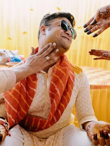 A relaxed groom enjoying his Haldi ceremony. The sunglasses add a touch of modern fun to the traditional event.