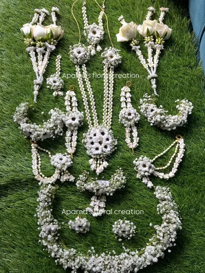 A complete baby shower set made with baby's breath and white roses. This set includes a tiara, necklace, earrings, haath phool, and bajuband.