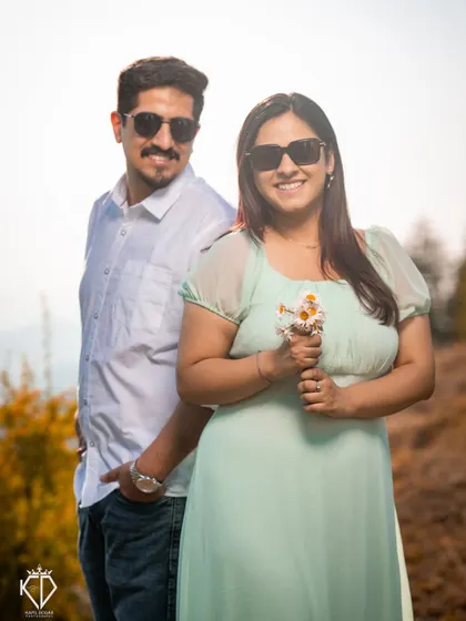 A playful portrait with the couple in sunglasses, her holding a small bunch of daisies. This image radiates fun and happiness.