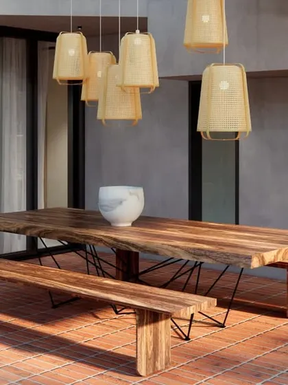 The outdoor dining area on the HAUS 5 terrace. A large live-edge wooden table and benches sit on earthy brick flooring, creating a perfect space for entertaining.
