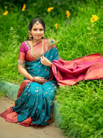 A serene portrait of the mom-to-be seated on the grass, her colorful saree and the green surroundings creating a vibrant picture.