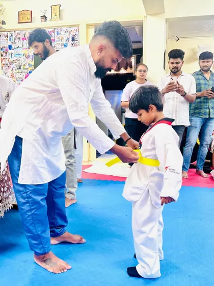 A proud moment as I tie a new yellow belt on one of my youngest students. This is the first step on their Taekwondo path.