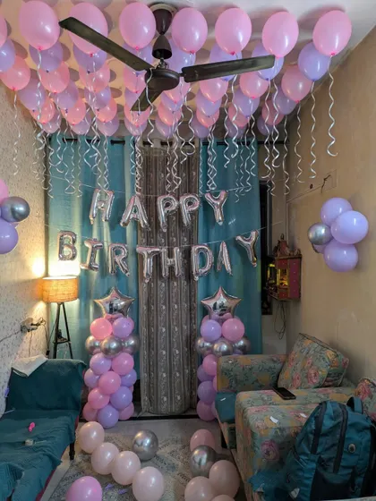 A frontal view of the birthday banner and balloon pillars, with dozens of balloons floating above.