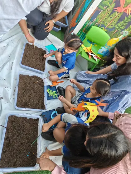 A group of children fully immersed in their dinosaur dig. They use brushes and tools to excavate, just like real paleontologists.