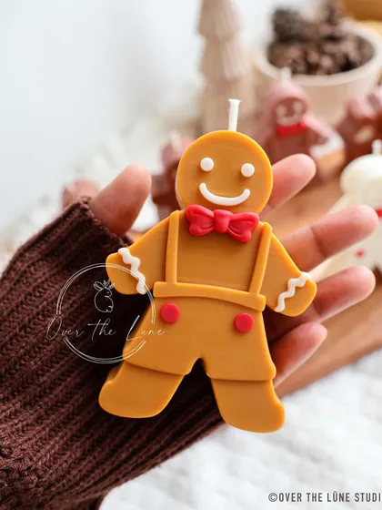 Holding one of my classic gingerbread man candles. The details, from the suspenders to the smile, are all carefully crafted by hand.