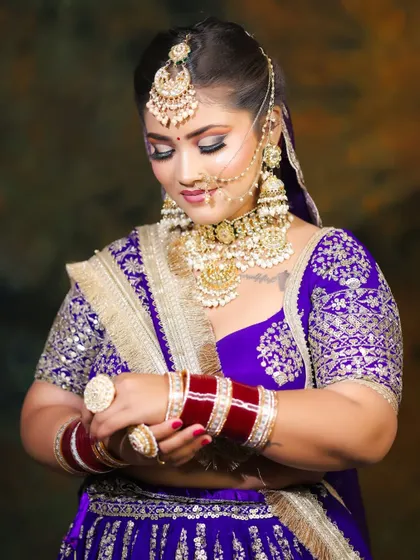 A candid-style shot showing the bride admiring her bangles. The makeup is designed to look beautiful from all angles, even in unposed moments.