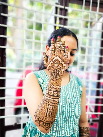 A happy bride peeking through her henna-covered hand.