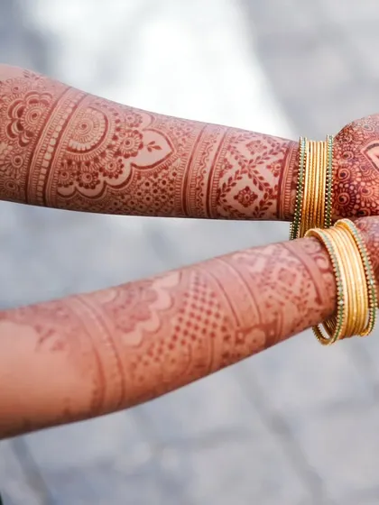 A clear view of matching henna designs on both arms. The pattern features a mix of floral and geometric elements, suitable for many different occasions.