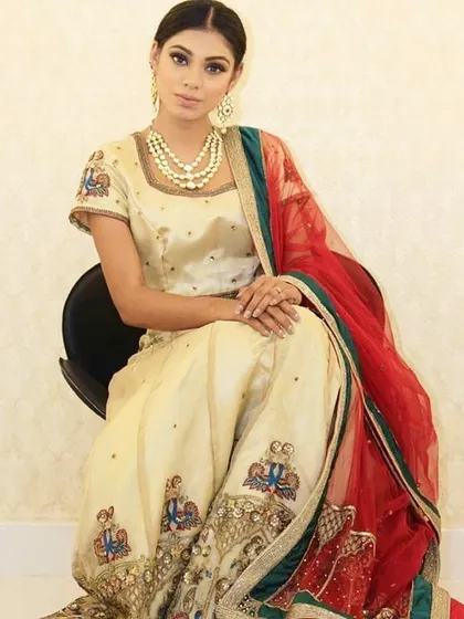 For the bride who loves subtle elegance, this pastel lehenga is a perfect choice. The delicate hand embroidery on the cream-colored fabric, paired with a vibrant red and green bordered dupatta, creates a soft and beautiful look.