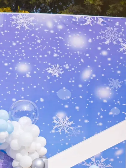 The snowflake-printed backdrop provides the perfect canvas for the balloon arrangements and party props.