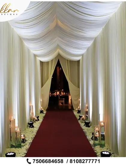 A simple yet incredibly elegant entrance. I used flowing white drapes to create a tunnel effect, with a red carpet and large candles lining the path for a dramatic and sophisticated welcome.