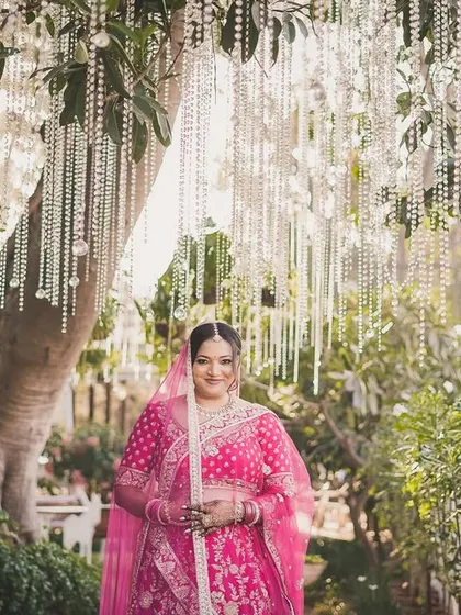 The bride, Nerissa, framed by a beautiful curtain of pearls at her outdoor wedding venue.