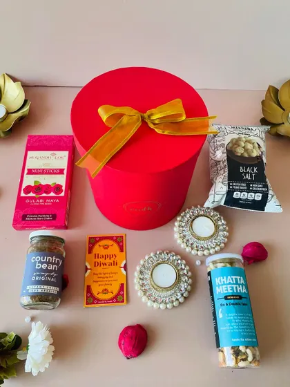 Our round red gift box is a popular choice for affordable gifting, filled with a delightful mix of coffee, snacks, and a diya.