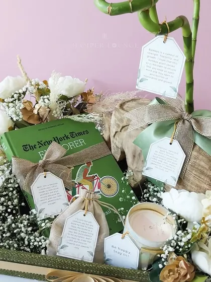 This detailed shot showcases the contents of the sustainable hamper. You can see a book, a scented candle, and items in small jute bags, each with a tag explaining its significance. It’s a gift that tells a story of mindfulness and care.