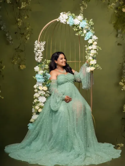 Seated like a queen on a floral-adorned birdcage chair, this mom-to-be looks serene in her flowing green gown.