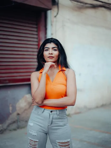 A confident portrait of a model against a red shuttered wall. Her direct gaze and strong pose make this a very engaging street style shot.