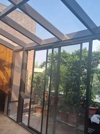 This angle shows how our glass extension integrates with the home's interior, featuring wood-paneled walls and a seamless transition. The transparent roof and walls make the space feel expansive and bright.