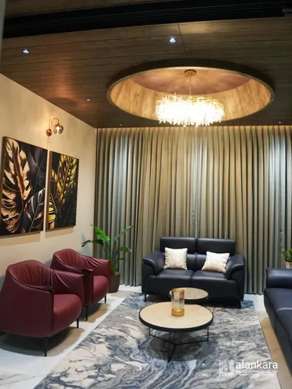 A sophisticated living room featuring a custom black leather sofa set paired with bold red armchairs. The space is unified by a dramatic ceiling design with a central chandelier and elegant full-length curtains.