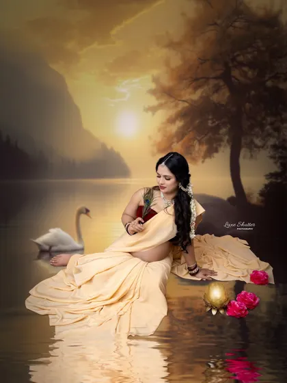 A serene, painterly portrait of a mother-to-be as 'Maiyya' Yashoda. Dressed in a simple saree by a tranquil lake, she holds a peacock feather, evoking a divine and peaceful mood.